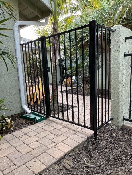 A gated entry to a home with a brick walkway.