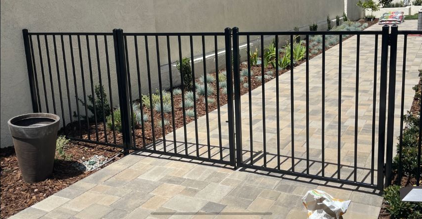 A patio with a stone walkway and a metal fence.
