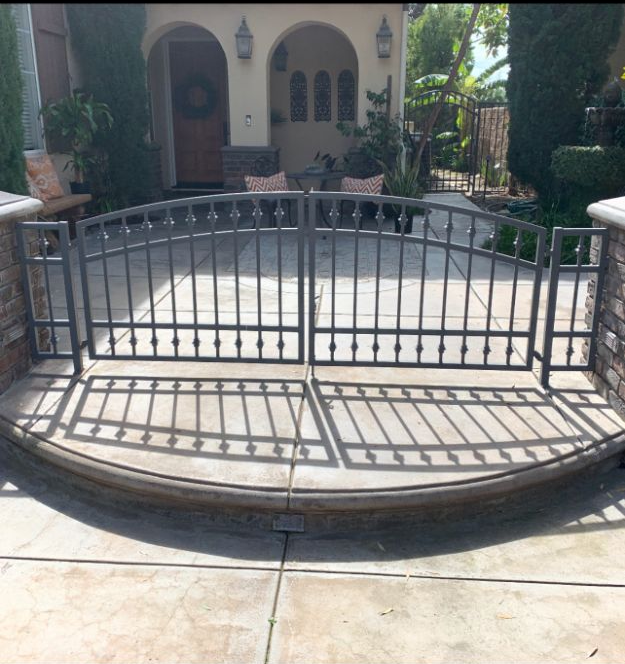 A curved metal gate in front of a house.