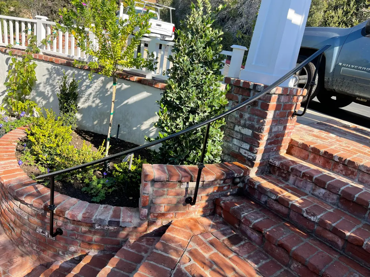 A brick staircase with wrought iron railing.