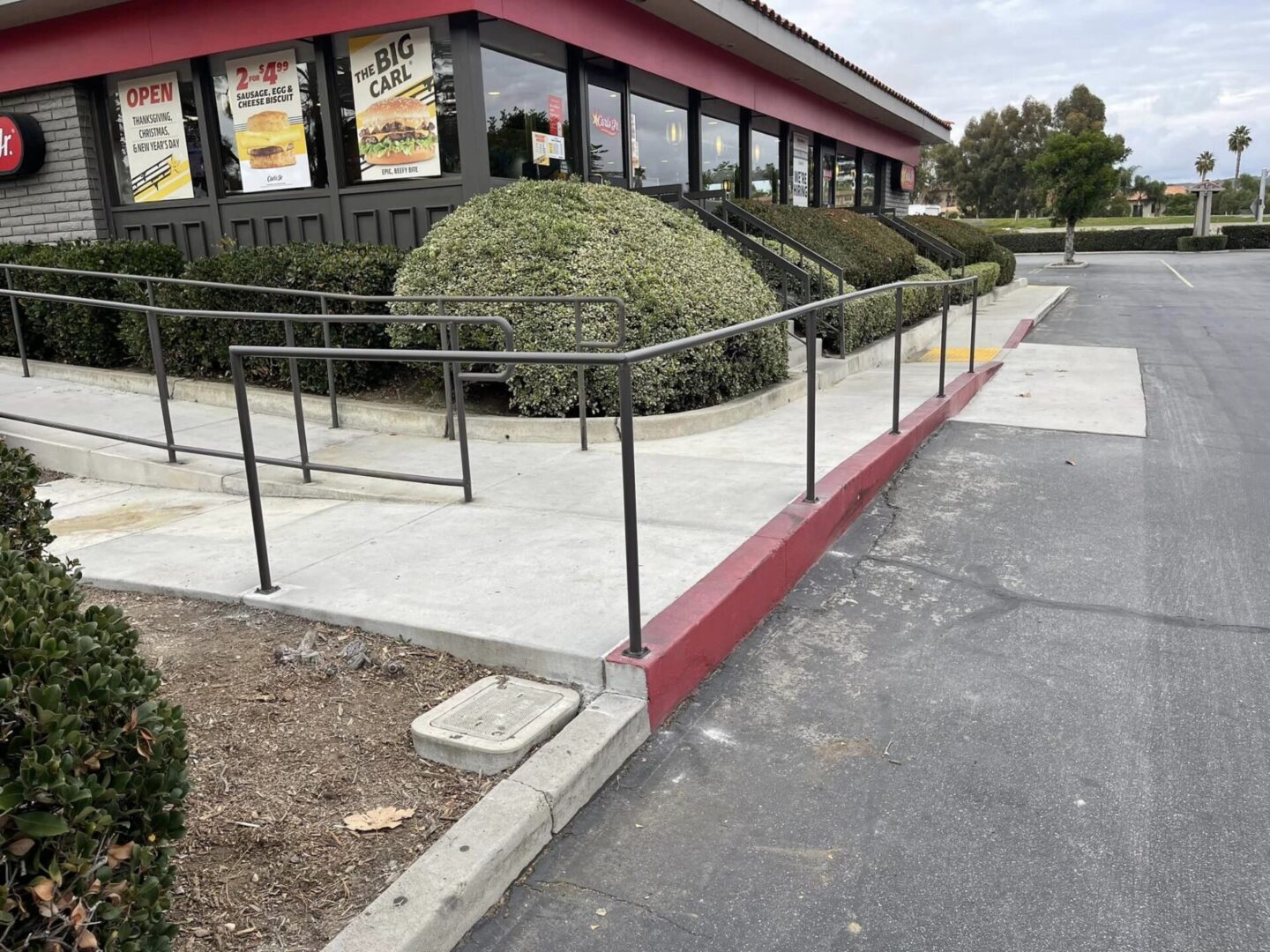 A restaurant with a fence around it and bushes in the background.