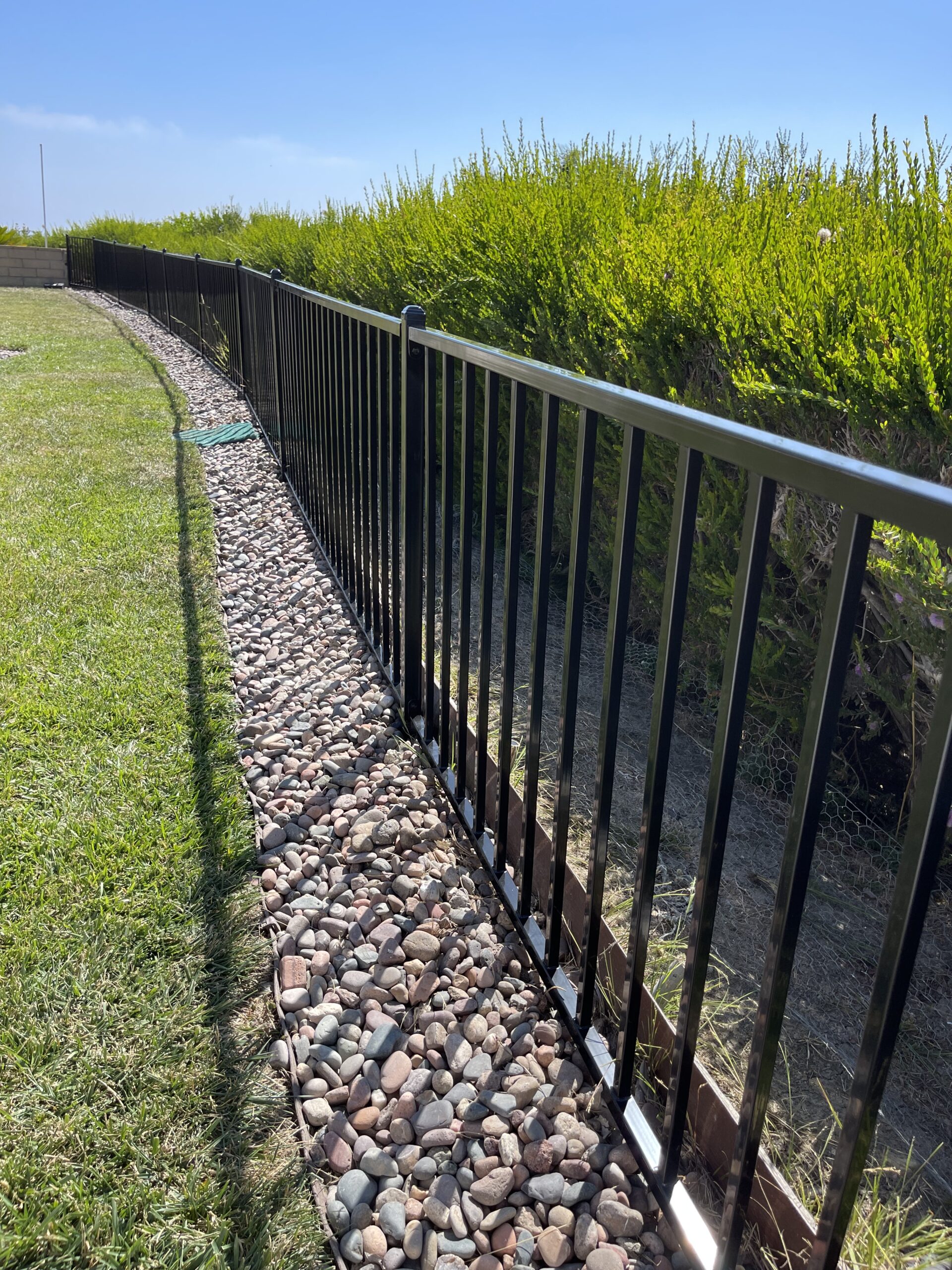 A fence with a stone path leading to the side of it.