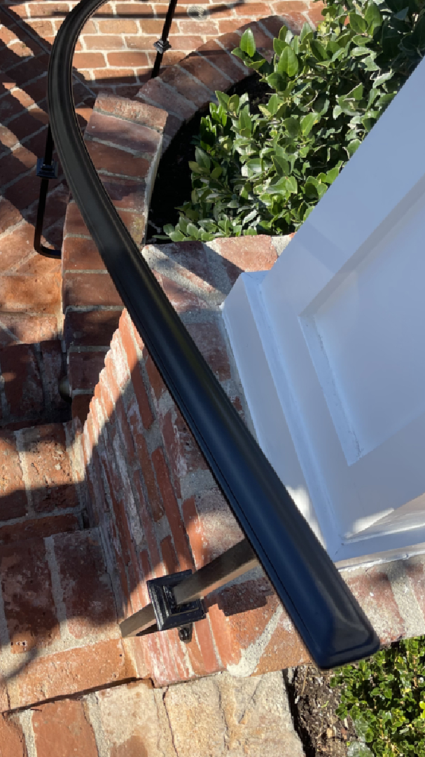 Curved black handrail on brick steps.