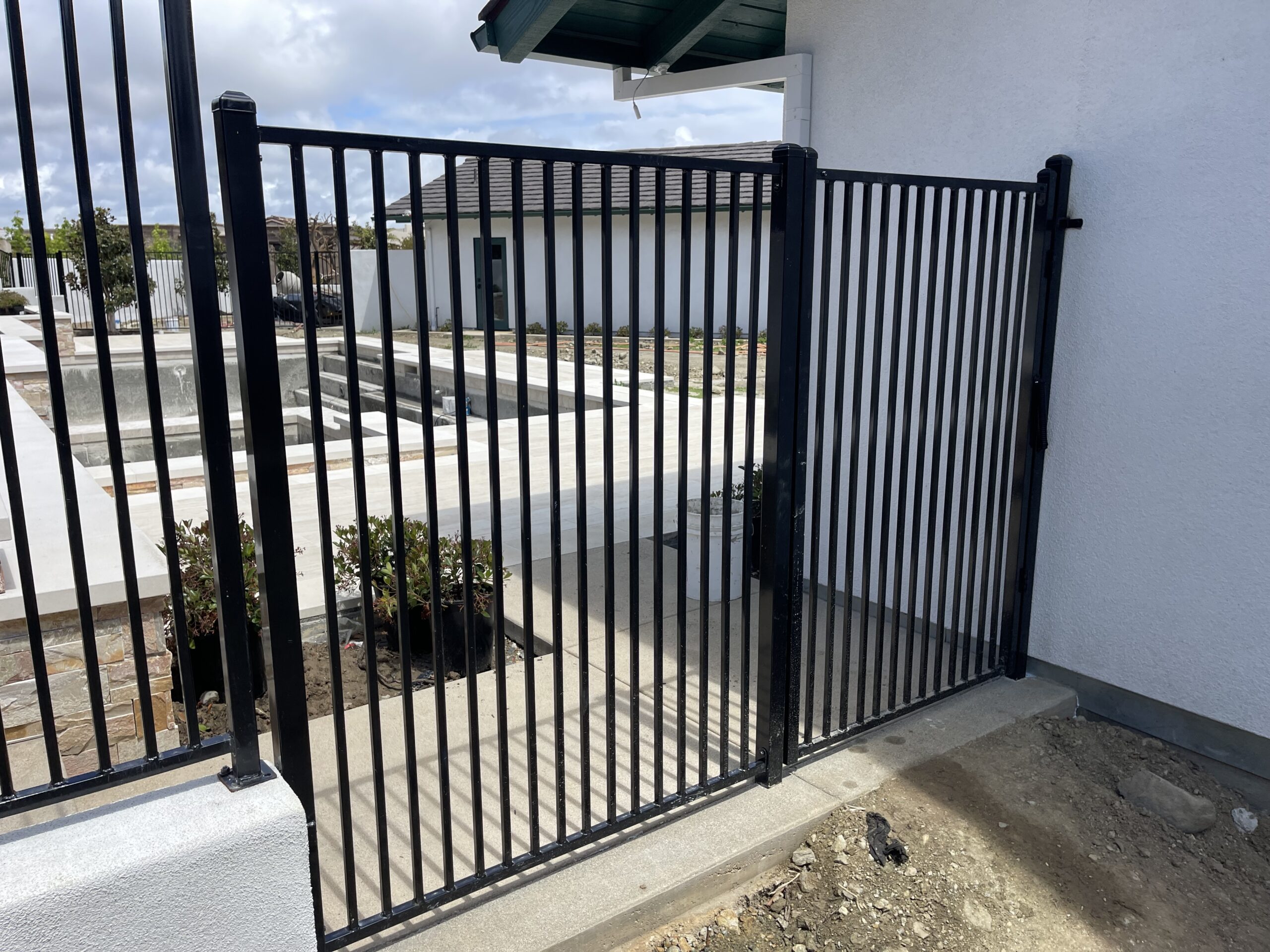 Black metal gate beside a white building.
